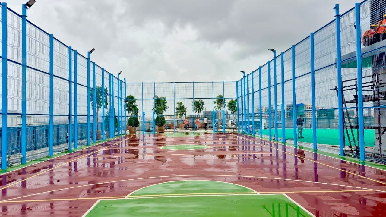 High blue perimeter fencing panels paired with synthetic acrylic sports turf surface