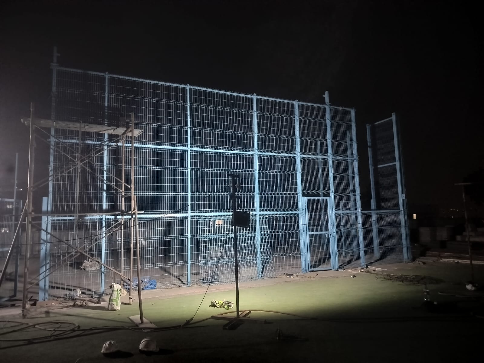 Mesh panel attachment under night floodlighting